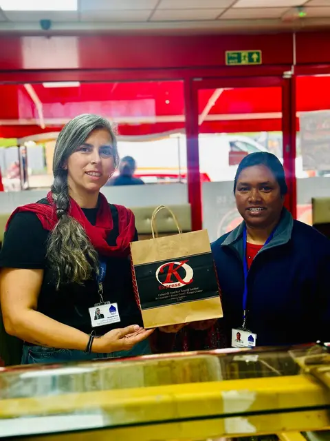 A Kulcha Express team member handing a packed meal to a community member