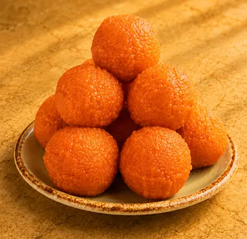 Plate of bright orange motichoor ladoo stacked in a pyramid